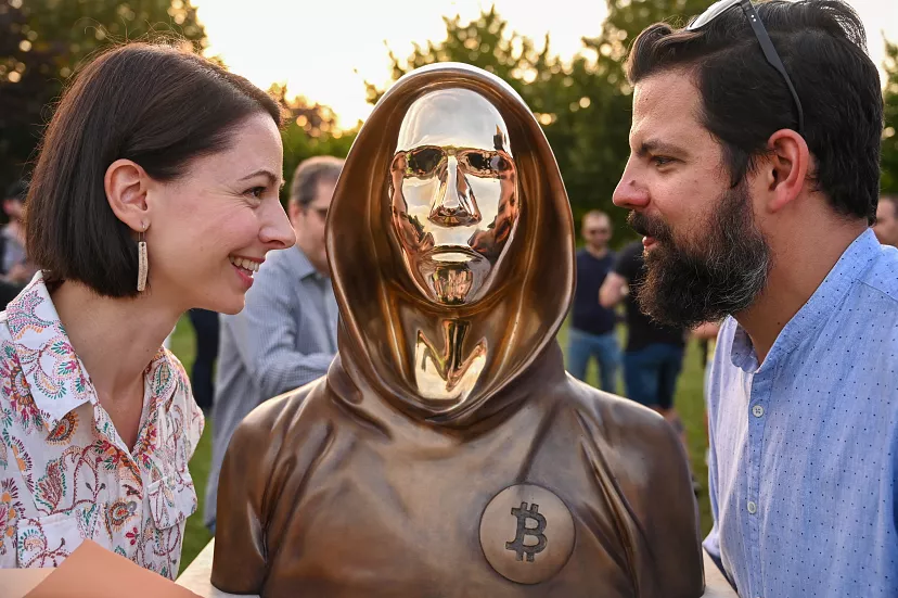 Los escultores húngaros Reka Gergely y Tamas Gilli posan junto al monumento a Satoshi Nakamoto, fundador de Bitcoin.